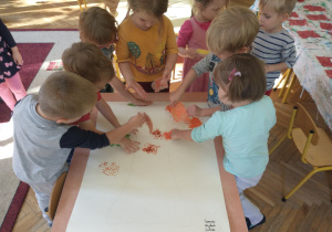 Dzieci wykonują pracę plastyczną - ozdabiają drzewo farbą